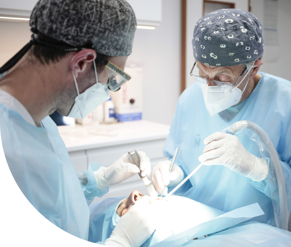 Dos dentistas con uniforme azul realizando una operación
