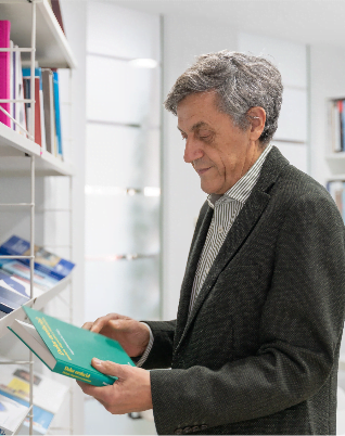 Hombre con traje mirando un libro verde en frente de una estanteria
